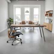 Doğal ışıkta metal ayaklı masa, ergonomik sandalye ve toplantı alanı görünen modern ofis